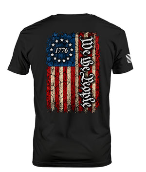 Black short-sleeve t-shirt with a distressed American flag graphic on the back, featuring 'We the People' in gothic lettering and '1776' in a star circle.