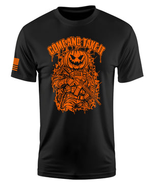 A black short-sleeve crewneck t-shirt with a large orange graphic on the front showing a soldier with a pumpkin head and the text 'GOMBAD TAKE IT'. A small orange flag graphic is printed on the right sleeve.
