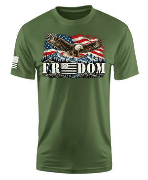 An olive green short-sleeve t-shirt with a patriotic graphic on the chest featuring an eagle, an American flag, mountains, and the word 'FREEDOM'. A small black-and-white American flag is printed on the right sleeve.