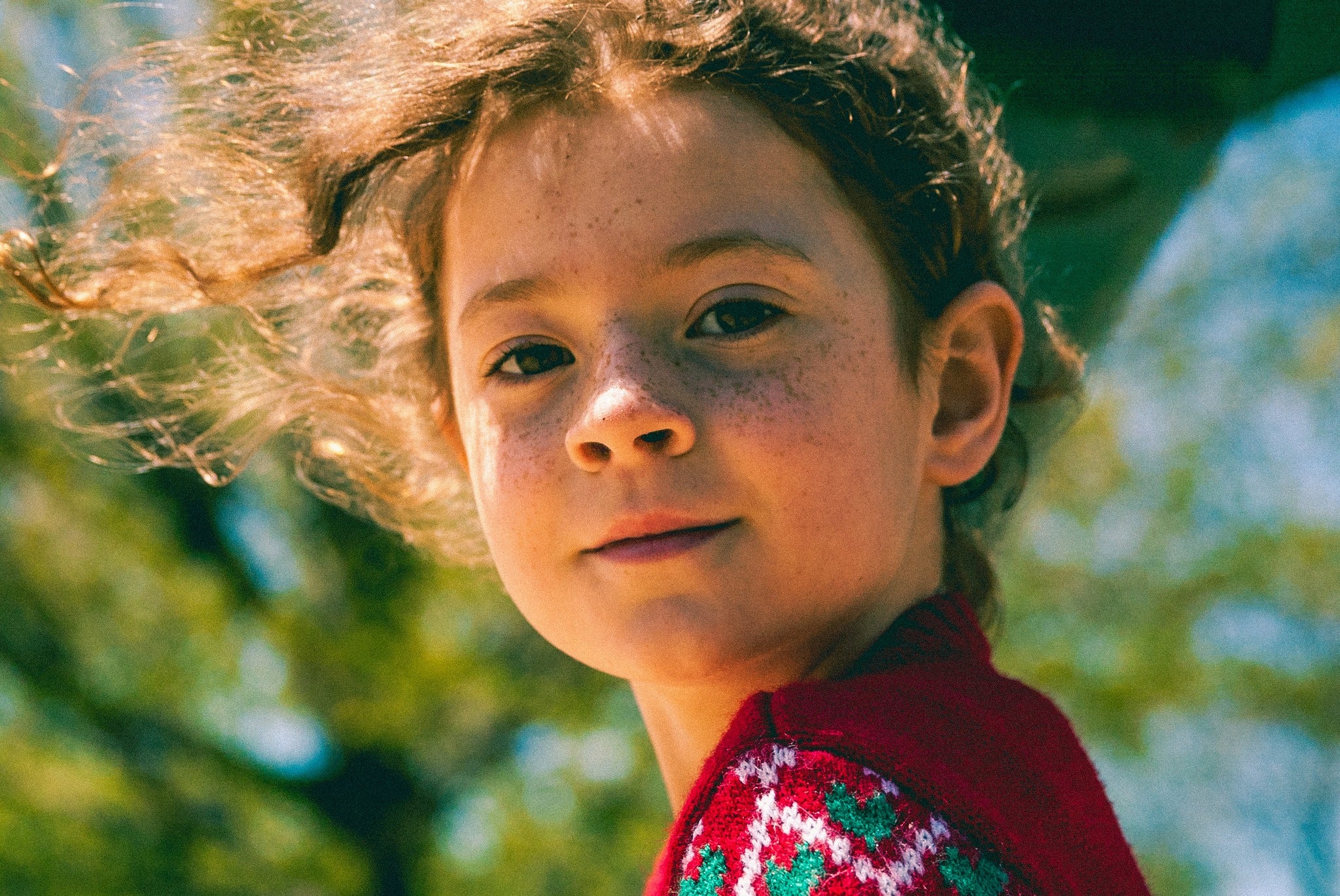 Gyllionna Gardner red sweater standing outdoors with trees in the background