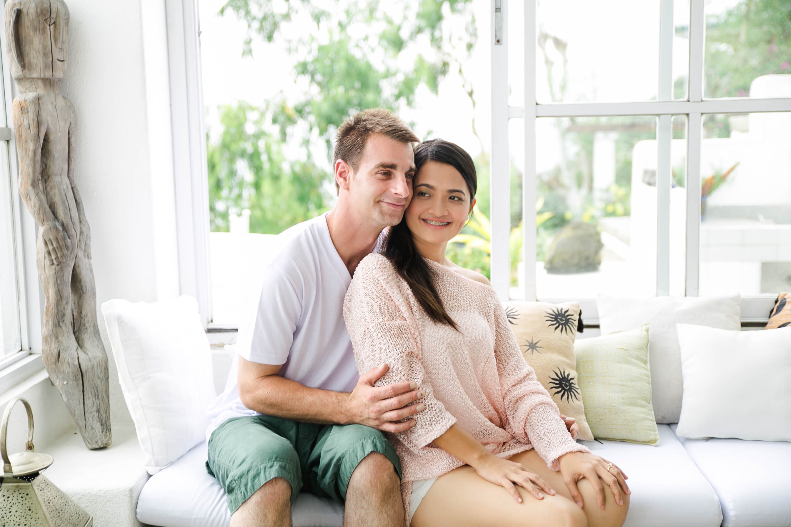 Justin and Jasmin sitting on a couch together in a bright room with large windows.